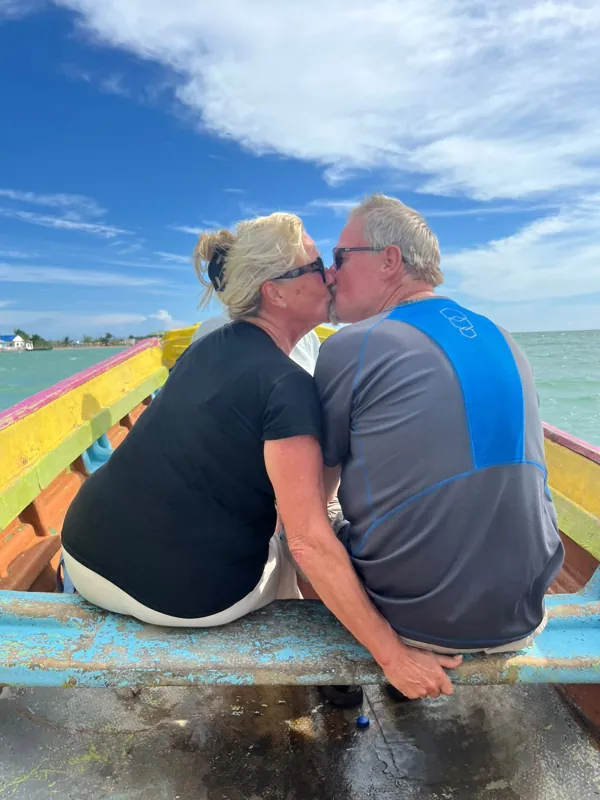 Two guests sitting together at the front of a small colourful boat