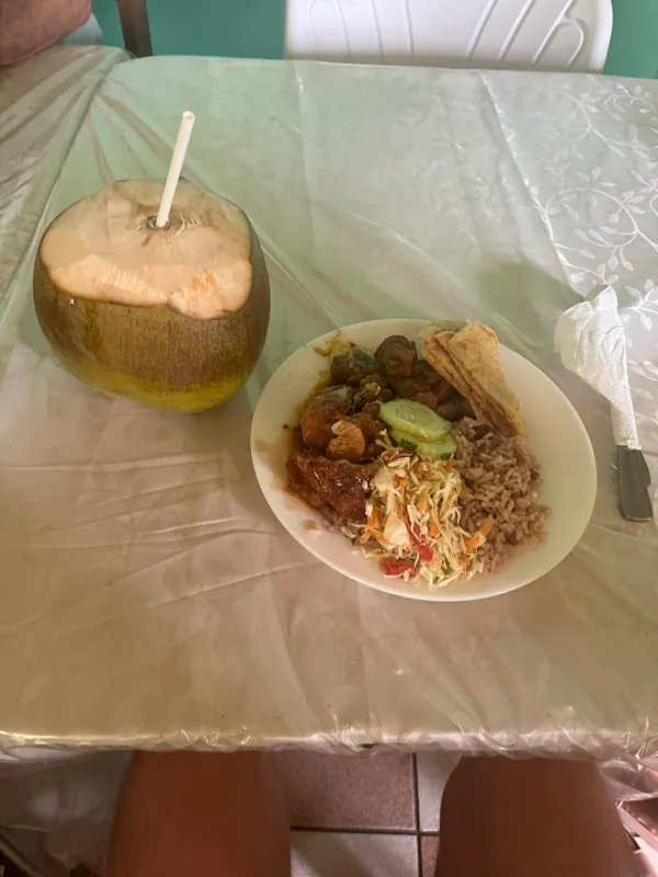 A fresh coconut beside a plate of food at a local restaurant