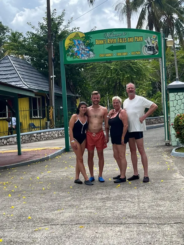 Four guests posing beneath the Dunn’s River Falls entrance sign
