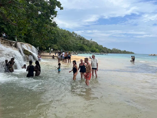 Visitors beside waterfalls flowing onto a beach