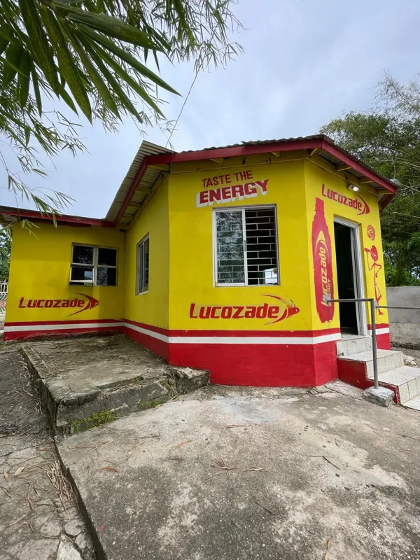 A small yellow and red roadside restaurant under palm trees