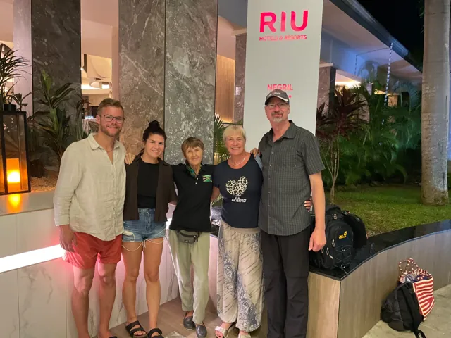 A small group beside a tour vehicle at a hotel entrance